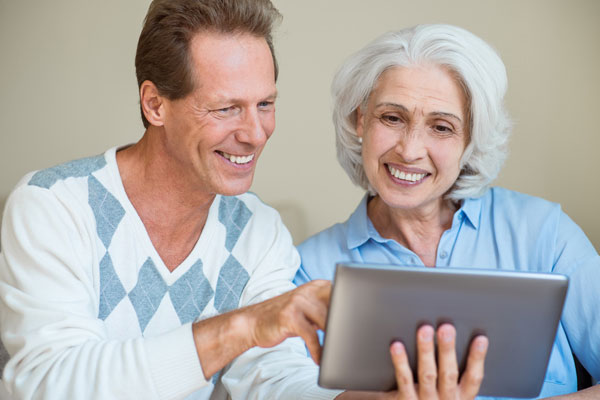 Smiling adult son and older mom looking at tablet computer.