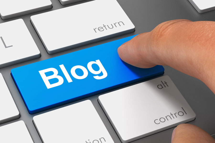 Finger pressing computer key that says the word blog on it.