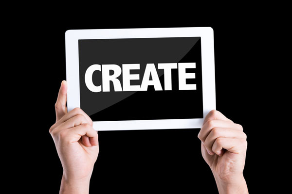 Two hands holding tablet computer screen with create text on it.