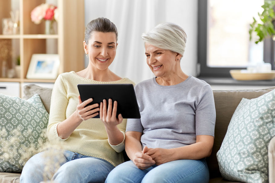 Older mom and daughter viewing home care content on computer.