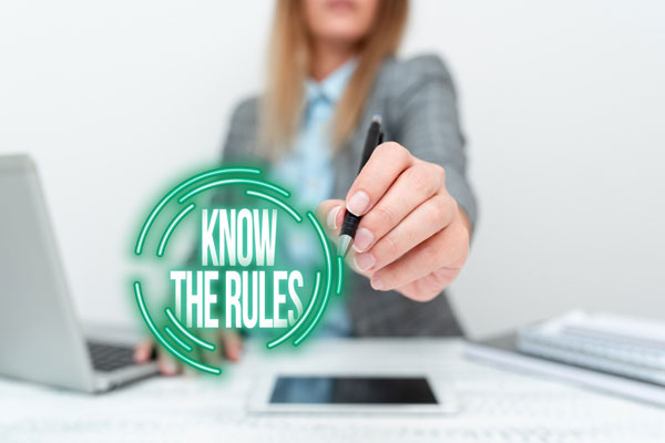 Businesswoman at computer pointing to know the rules text.