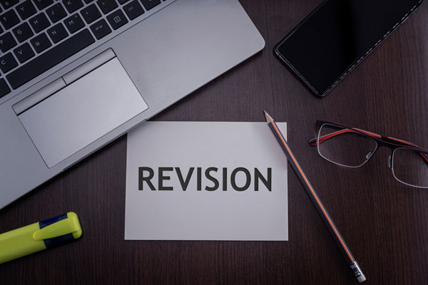 Laptop, phone and revision text on paper.