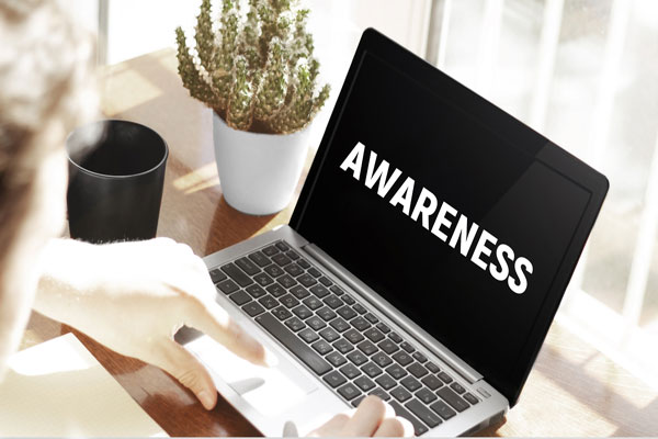 Person typing on laptop that has word awareness on the screen.