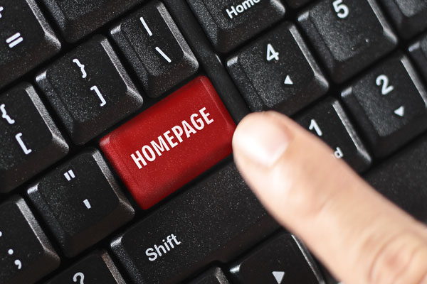 Keyboard with word homepage on computer key that finger is pressing.
