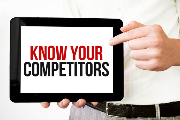 Man holding computer tablet with words know your competitors on screen.